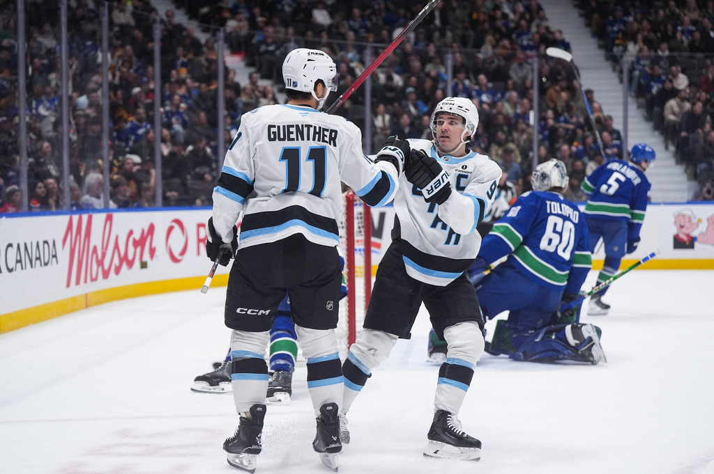 Utah Mammoth's Dylan Guenther (11) and Clayton Keller (9) celebrate Guenther's goal against Vancouver Canucks goalie Nikita Tolopilo (60) during the second period of an NHL hockey game, in Vancouver, on Saturday, April 4, 2026. (Darryl Dyck/The Canadian Press via AP)