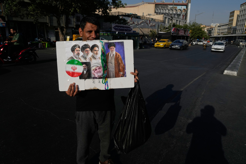 A man displays a placard with portraits of the current and late supreme leaders and the late Revolutionary Guard Gen. Qassem Soleimani at the Islamic Revolution Square in downtown Tehran, Iran, Saturday, July 18, 2026. (AP Photo/Vahid Salemi)