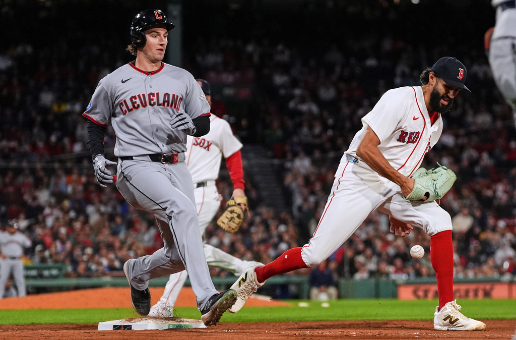 Cleveland Guardians' Chase DeLauter, left, reaches first base on a fielding error by pitcher Raymond Burgos, right, during the ninth inning of a baseball game, Thursday, Sept. 24, 2026, in Boston. (AP Photo/Charles Krupa)