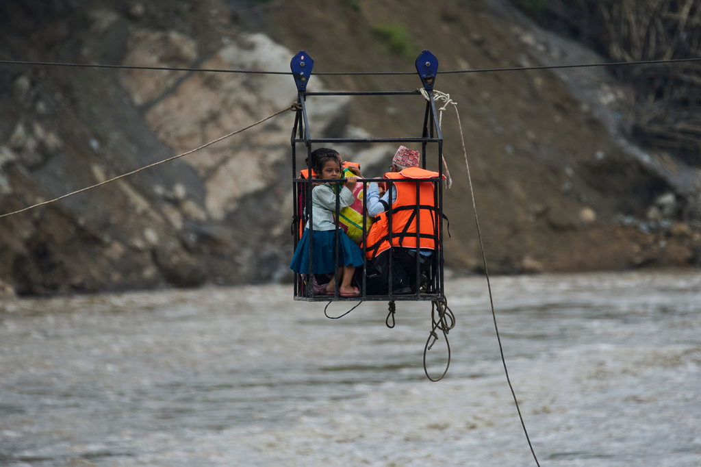 A young girl with her parents commute across the Trishuli river on a newly installed zipline in the aftermath of flash floods at Bidur, Nuwakot district, Nepal, Saturday, Sept. 5, 2026. (AP Photo/Niranjan Shrestha)