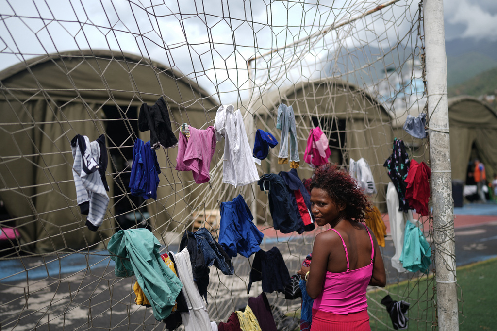 Nataly Mayora hangs clothes to dry on a soccer goal net as she does laundry at a sports center sheltering people displaced by the earthquakes in La Guaira, Venezuela, Thursday, July 9, 2026. (AP Photo/Ariana Cubillos)