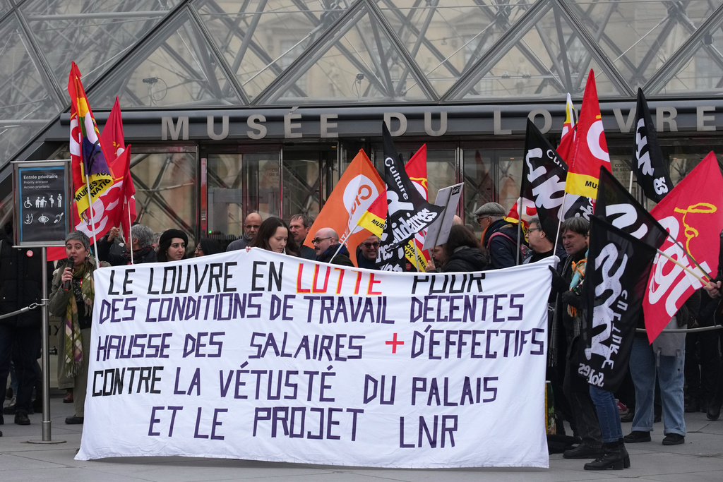 Unionists display a banner and union flags outside the Louvre museum after employees have voted to extend a strike that has disrupted operations at the world's most visited museum, Wednesday, Dec. 17, 2025 in Paris. (AP Photo/Christophe Ena)