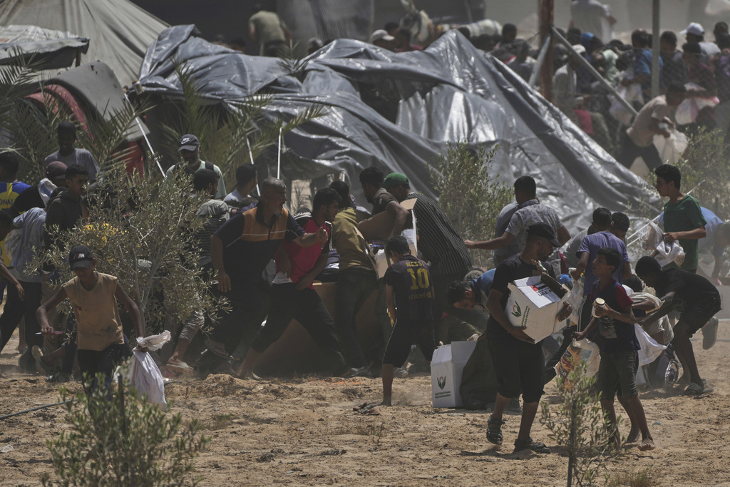 Palestinians rush to collect humanitarian aid packages from the United Arab Emirates, airdropped by parachutes into Deir al-Balah, in the central Gaza Strip, Tuesday, Aug. 19, 2025. (AP Photo/Abdel Kareem Hana)