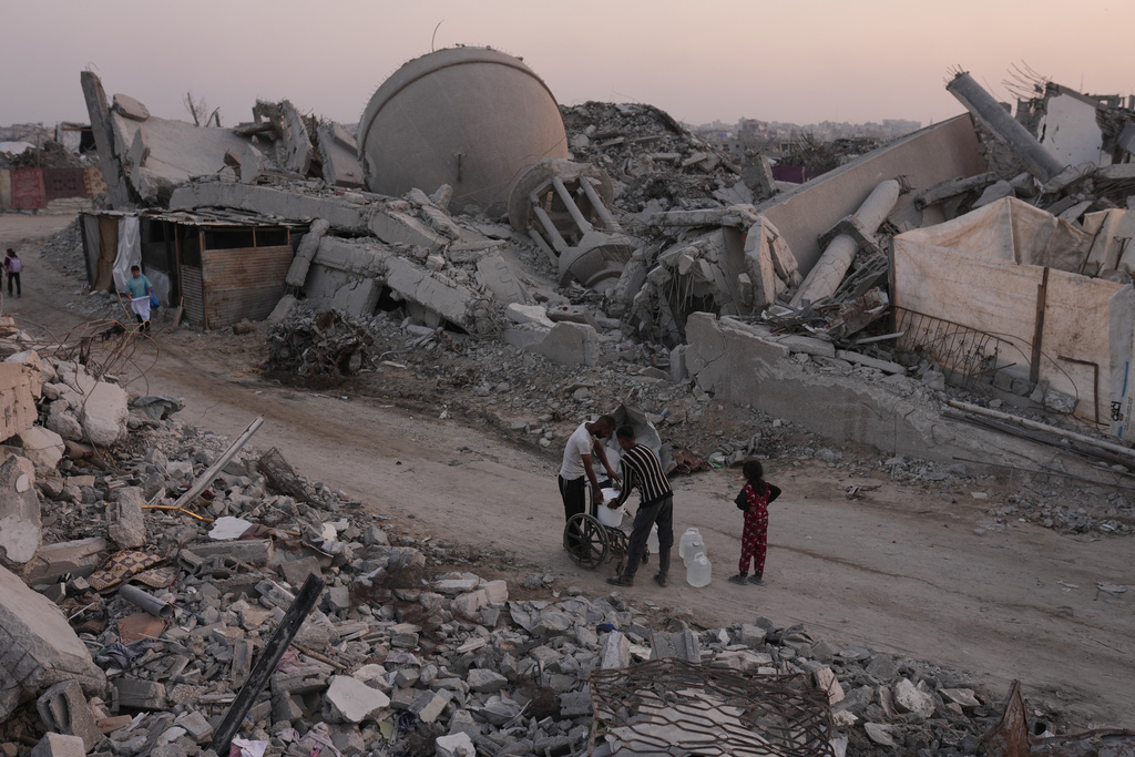 Palestinians carry water through the destruction caused by the Israeli air and ground offensive in Sheikh Radwan neighborhood in Gaza City, Monday, Nov. 10, 2025. (AP Photo/Jehad Alshrafi)