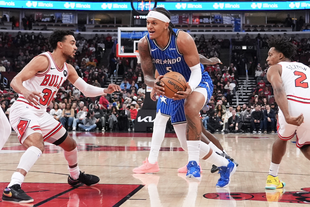 Orlando Magic forward Paolo Banchero (5) drives to the basket against Chicago Bulls guards Tre Jones, left, and Collin Sexton during the first half of an NBA basketball game in Chicago, Friday, April 10, 2026. (AP Photo/Nam Y. Huh)