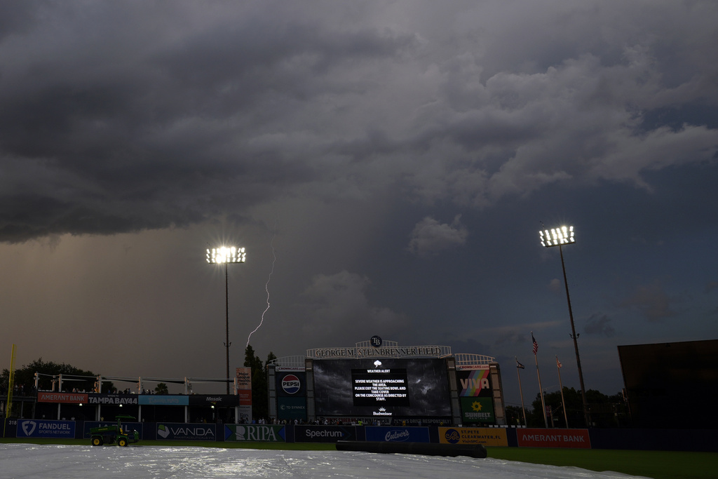 A lightning bolt strikes beyond the outfield wall delaying the start of a baseball game between the Tampa Bay Rays and the New York Yankees Tuesday, Aug. 19, 2025, in Tampa, Fla. (AP Photo/Chris O'Meara)