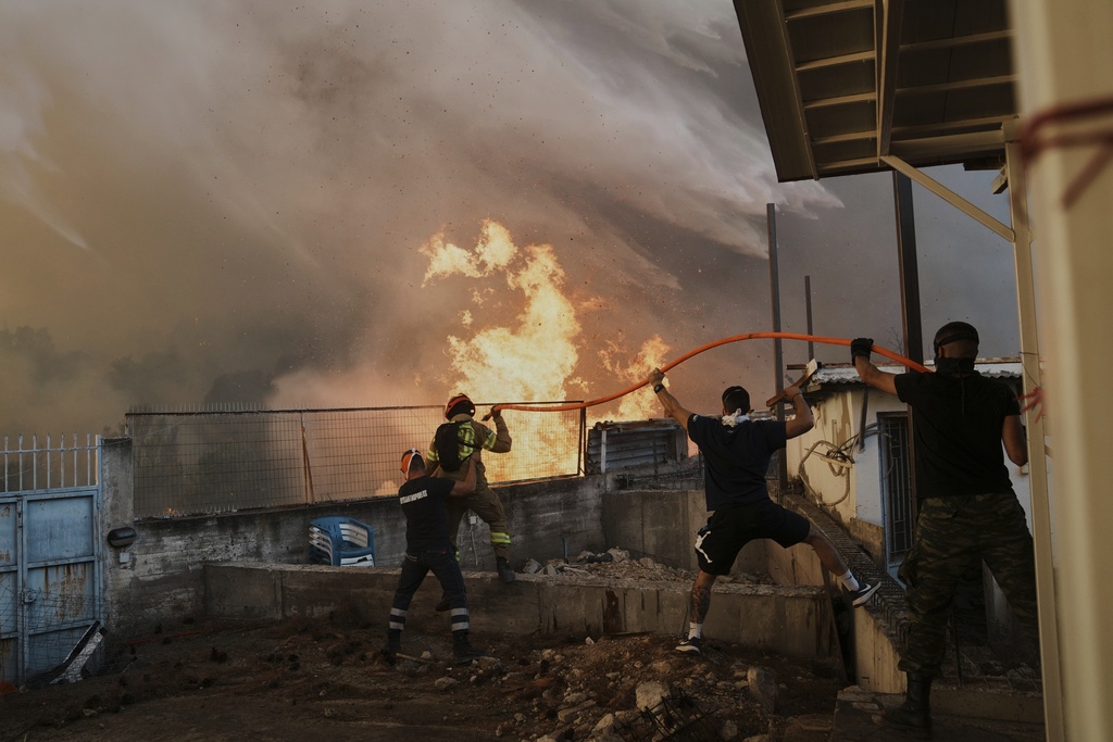 FILE - A firefighter and men try to control the flames approaching a house during a wildfire in Patras city, western Greece, Aug. 13, 2025. (AP Photo/Thanassis Stavrakis, File)