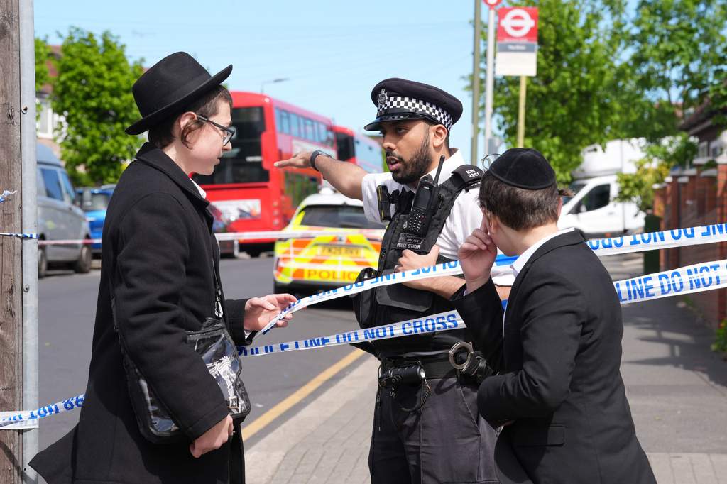 A Police officer talks with two boys at the scene where two people were stabbed Wednesday April 29, 2026 in a London neighborhood with a large Jewish community and a 45-year-old man was arrested on suspicion of attempted murder over what authorities called an antisemitic attack. (Lucy North/PA via AP)