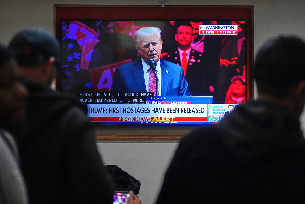 FILE - People inside of a restaurant watch President-elect Donald Trump on television with subtitles as he speaks during a rally, Jan. 19, 2025, in Washington. (AP Photo/Julio Cortez, File)