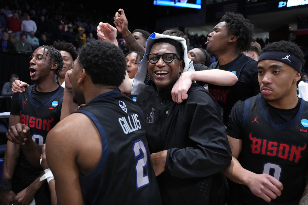 Howard head coach Kenneth Blakeney, center, and Howard players celebrate at the conclusion of the second half in a First Four college basketball game in the NCAA Tournament against UMBC, Tuesday, March 17, 2026, in Dayton, Ohio. (AP Photo/Kareem Elgazzar)