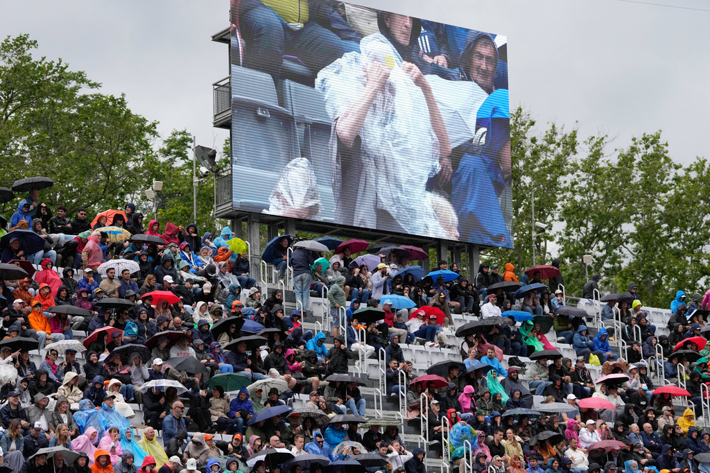 Spectators shelter from the rain during the quarter-final match between Karen Khachanov, of Russia, and Casper Ruud, of Norway, at the Italian Open tennis tournament in Rome, Wednesday, May 13, 2026. (AP Photo/Gregorio Borgia)