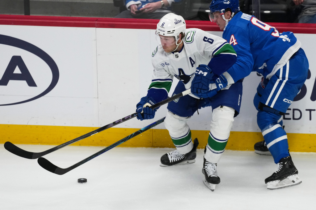 Vancouver Canucks right wing Brock Boeser, left, collects the puck as Colorado Avalanche left wing Joel Kiviranta defends in the second period of an NHL hockey game, Wednesday, April 1, 2026, in Denver. (AP Photo/David Zalubowski)