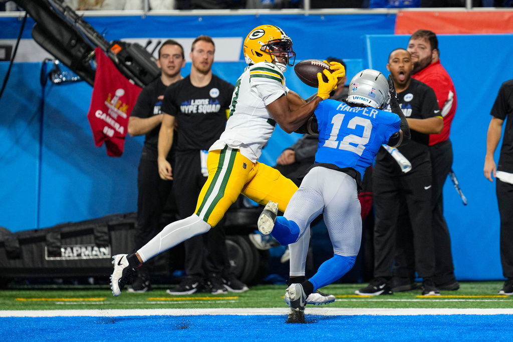 Green Bay Packers wide receiver Dontayvion Wicks (13) makes a catch in front of Detroit Lions safety Thomas Harper (12) for a touchdown during the first half an NFL football game in Detroit, Thursday, Nov. 27, 2025. (AP Photo/Paul Sancya)