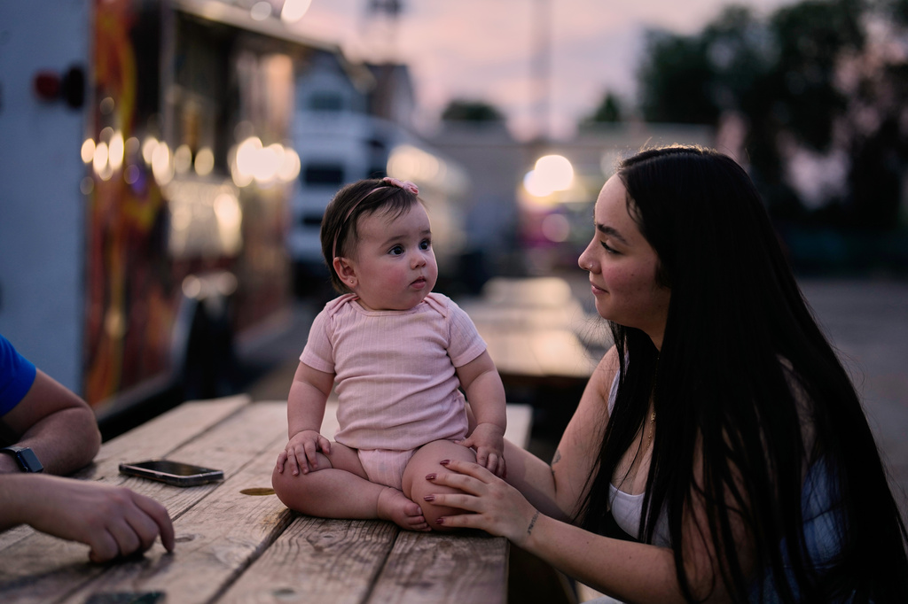 A Venezuelan mother sits with her daughter among food trucks Tuesday, July 14, 2026, in Midvale, Utah. (AP Photo/Gregory Bull)