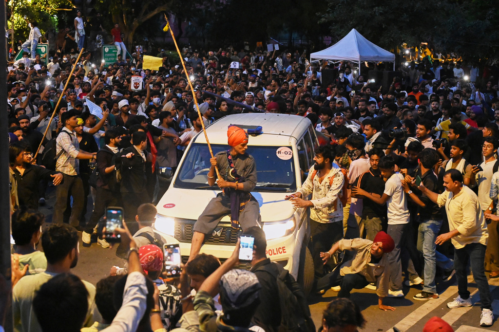 A protestor sits on the hood of a police car during a demonstration demanding educational reforms as part of the Cockroach Janta Party's ongoing protest movement in New Delhi, India, Wednesday, July 22, 2026. (AP Photo/Vipin)