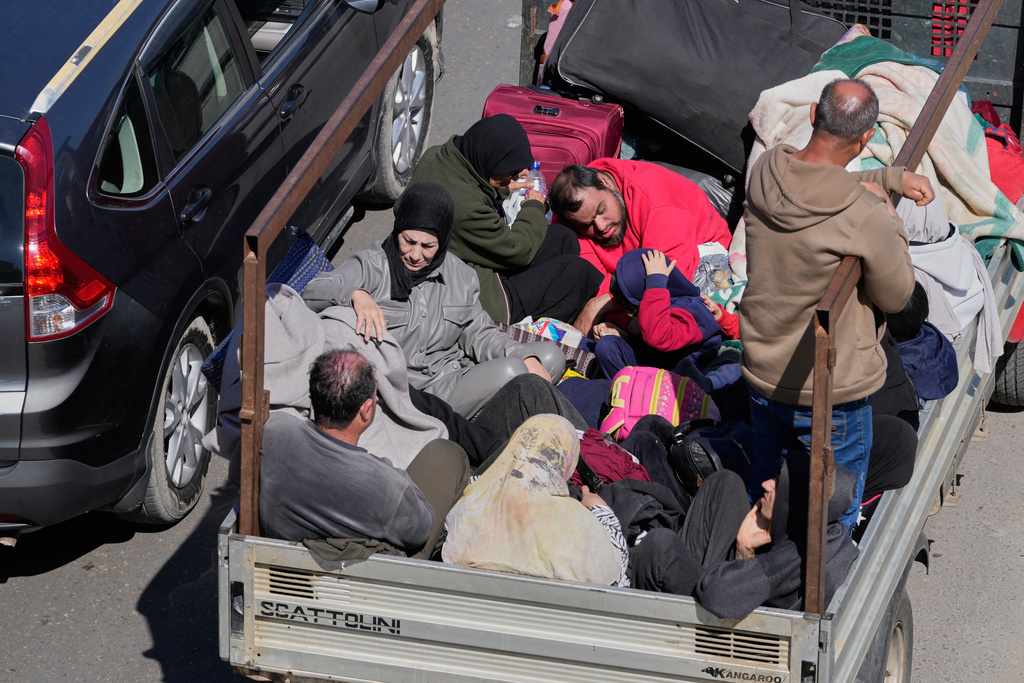 A displaced family fleeing Israeli airstrikes in southern Lebanon, sit in the back of a pickup truck along a highway toward Beirut, in the southern port city of Sidon, Lebanon, Tuesday, March 3, 2026. (AP Photo/Mohammed Zaatari)