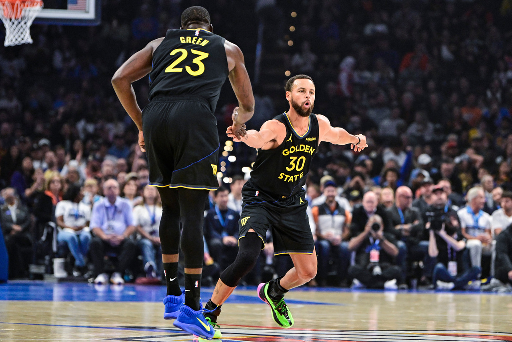 Golden State Warriors guard Stephen Curry (30) celebrates with Golden State Warriors forward Draymond Green (23) during the first half of an NBA basketball game, Tuesday, Nov. 11, 2025, in Oklahoma City. (AP Photo/Gerald Leong)