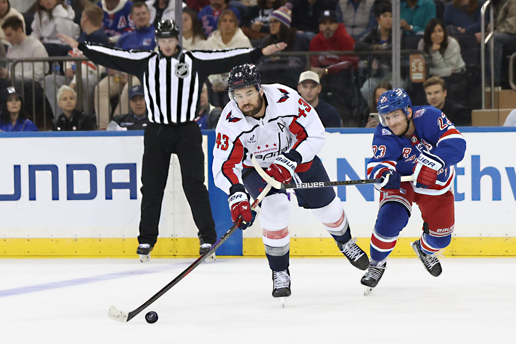New York Rangers' Adam Fox (23) reaches for the puck behind Washington Capitals' Tom Wilson (43) during the second period of an NHL hockey game, Sunday, Oct. 12, 2025, in New York. (AP Photo/Heather Khalifa)