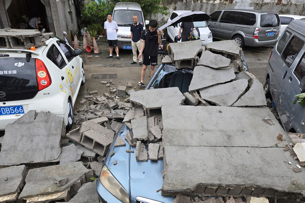 Residents view cars damaged by a fallen wall in the aftermath of Typhoon Dolphin in Wenzhou in eastern China's Zhejiang province, Monday, Aug. 10, 2026. (Chinatopix via AP)