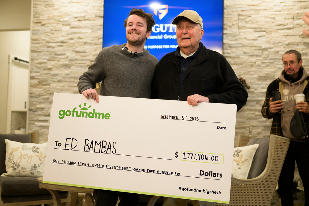 Influencer Samuel Weidenhofer, left, poses for a photo with Ed Bambas, right, the 88-year-old Brighton resident who is the recipient of over $1.7 million after a viral Gofundme campaign was started by Weidenhofer, after the amount is revealed to Bambas, Friday, Dec. 5, 2025, in Brighton, Mich. (Katy Kildee/Detroit News via AP)