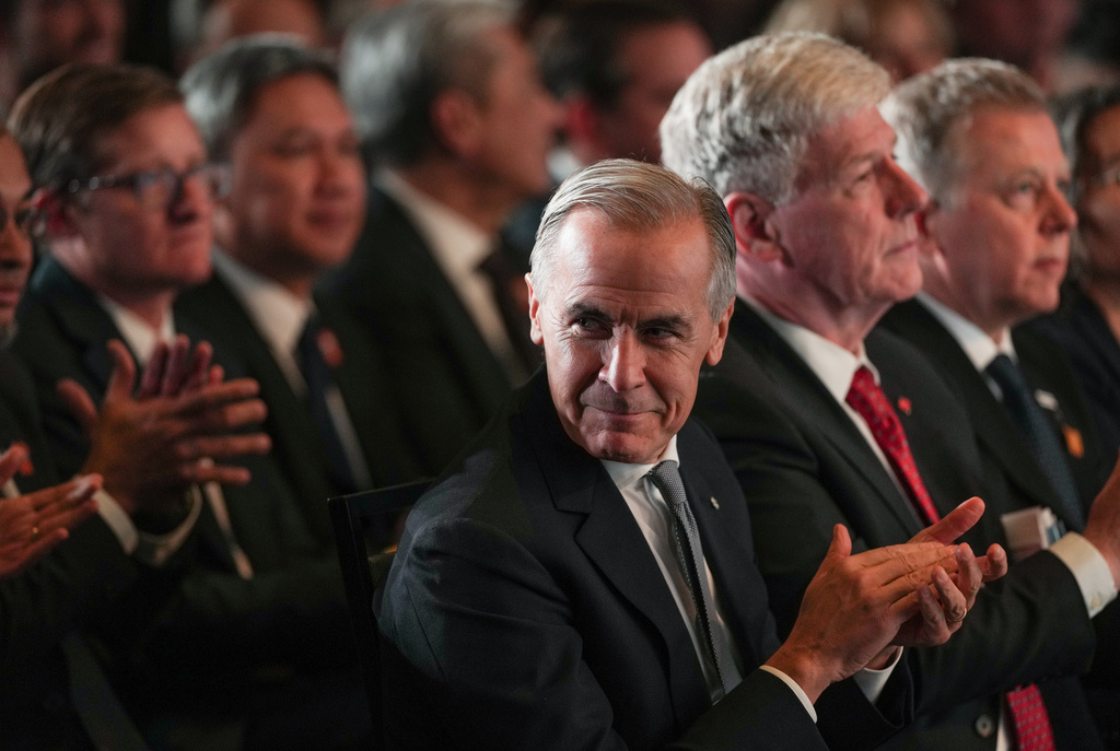 Canada Prime Minister Mark Carney applauds while sitting with Minister of Energy and Natural Resources Tim Hodgson before speaking after LNG Canada said it will go ahead with the Phase 2 expansion project at its LNG terminal in Kitimat, British Columbia, Canada, during an announcement in Vancouver, on Tuesday, Sept. 29, 2026. (Darryl Dyck/The Canadian Press via AP)