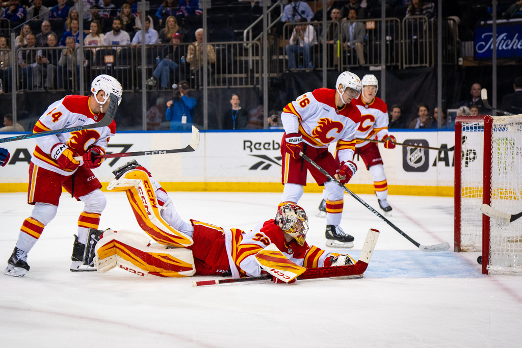 Calgary Flames goaltender Dustin Wolf (32) falls as the New York Rangers score a third goal, during the second period of an NHL hockey game, Tuesday, March 10, 2026, in New York. (AP Photo/Angelina Katsanis)