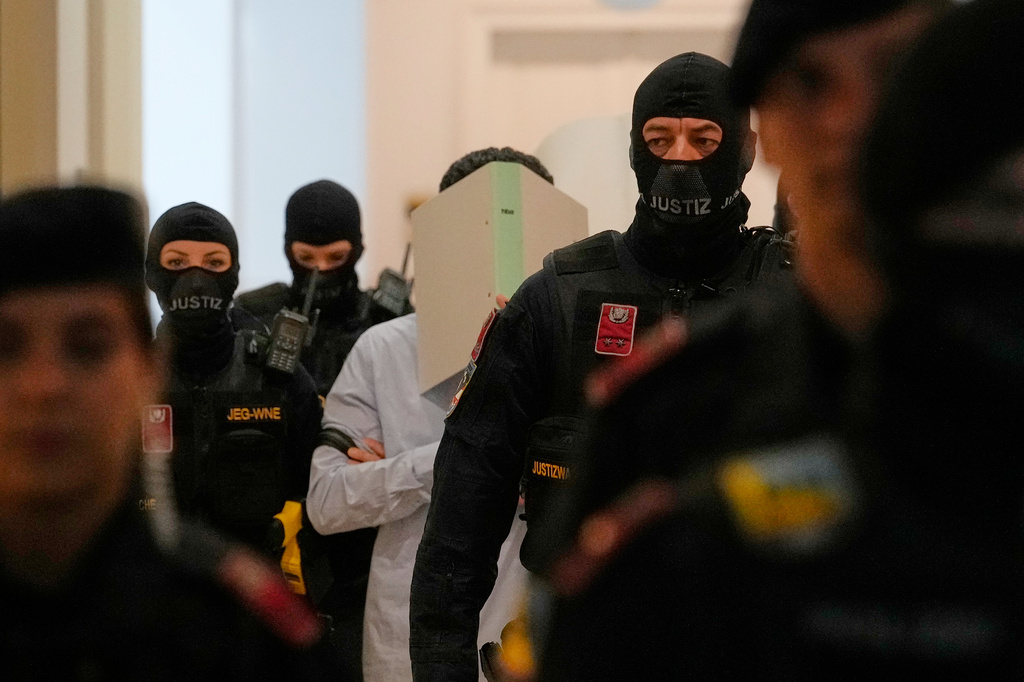 The defendants hide their faces behind file folders on their way to the courtroom in the District Court in Wiener Neustadt, Austria, where two terror suspects will stand trial Tuesday, one for plotting to carry out an attack on one of superstar singer Taylor Swift's concerts in Vienna in August 2024 and pledging allegiance to the Islamic State group, Tuesday, April 28, 2026. (AP Photo/Matthias Schrader)