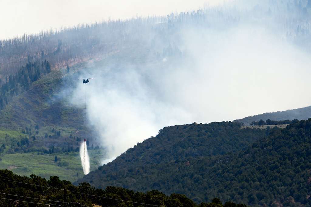 A helicopter drops water on the Cottonwood Fire burning near Beaver, Utah, on Saturday, June 27, 2026. (AP Photo/Noah Berger)