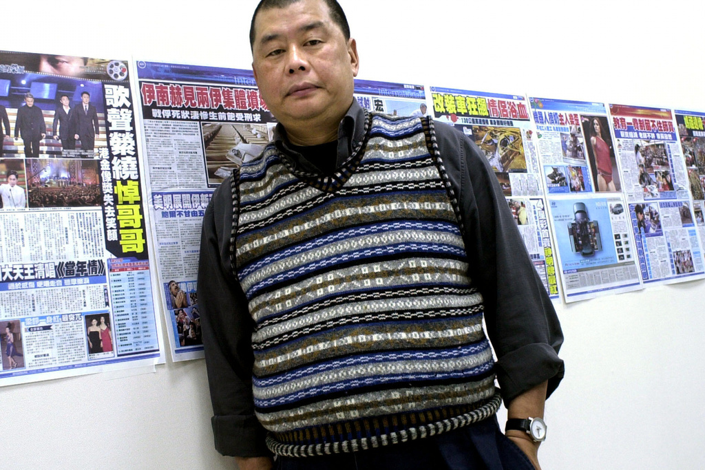 FILE - Jimmy Lai, owner of the Hong Kong newspaper Apple Daily, poses next to dry runs of a soon to be launched Taiwanese newspaper taped to his office wall, April 7, 2003, in Taipei. (AP Photo/Jerome Favre, File)