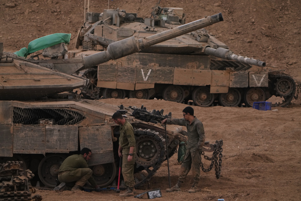 Israeli soldiers work on a tank near the Israeli-Gaza border, as seen from southern Israel, Thursday, Oct. 9, 2025, following the announcement that Israel and Hamas have agreed to the first phase of a peace plan to pause the fighting. (AP Photo/Ariel Schalit)