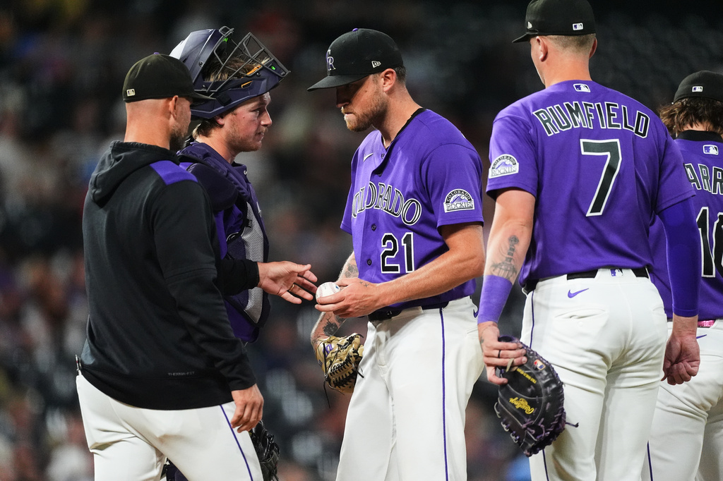 Colorado Rockies starting pitcher Kyle Freeland, center, hands the ball as he is pulled from the mound to manager Warren Schaeffer, front left, as catcher Hunter Goodman, back left, and first baseman TJ Rumfield look on in the fourth inning of a baseball game against the Arizona Diamondbacks Tuesday, Sept. 22, 2026, in Denver. (AP Photo/David Zalubowski)