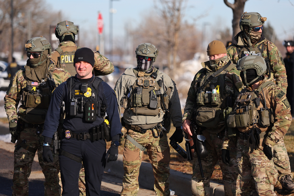 Federal agents stand outside the Bishop Henry Whipple Federal Building as protesters gather in Minneapolis, Friday, Jan. 9, 2026.(AP Photo/Adam Bettcher)