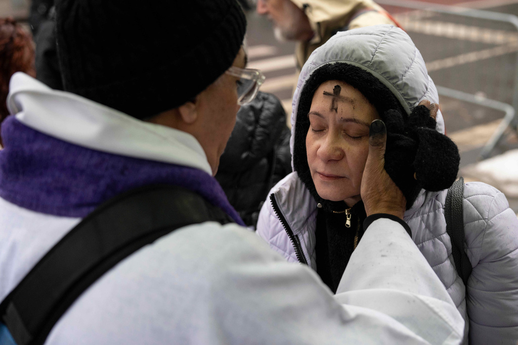 Father Fabian Arias places an ash cross on the forehead of a devotee during Ash Wednesday outside the Jacob K. Javits federal building, Wednesday, Feb. 18, 2026, in New York. (AP Photo/Yuki Iwamura)
