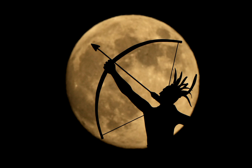 FILE - The bronze sculpture titled "Ad Astra," depicting a Kansa warrior, perched atop the Kansas State Capitol dome, is silhouetted against the nearly full moon, Nov. 14, 2024, on the eve of the final supermoon of the year in Topeka, Kan. (AP Photo/Charlie Riedel, File)