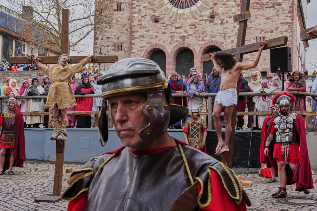 An amateur actor performing as Jesus, right, is fixed on a cross during the traditional Good Friday procession organised by the Italian community in Bensheim, Germany, Friday, April 3, 2026. (AP Photo/Michael Probst)
