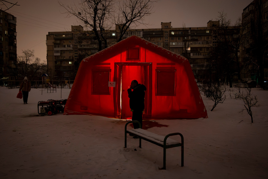 A man smokes outside of an emergency tent where people can warm up following Russia's regular air attacks against the country's energy objects, that leave residents without power, water and heating in the dead of winter, in Kyiv, Ukraine, Tuesday, Jan. 13, 2026. (AP Photo/Danyil Bashakov)