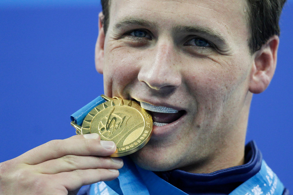 FILE - Ryan Lochte, of the United States, bites his gold medal for the men's 200 meters freestyle at the FINA Swimming World Championships in Shanghai, China, on July 26, 2011. (AP Photo/Michael Sohn, File)