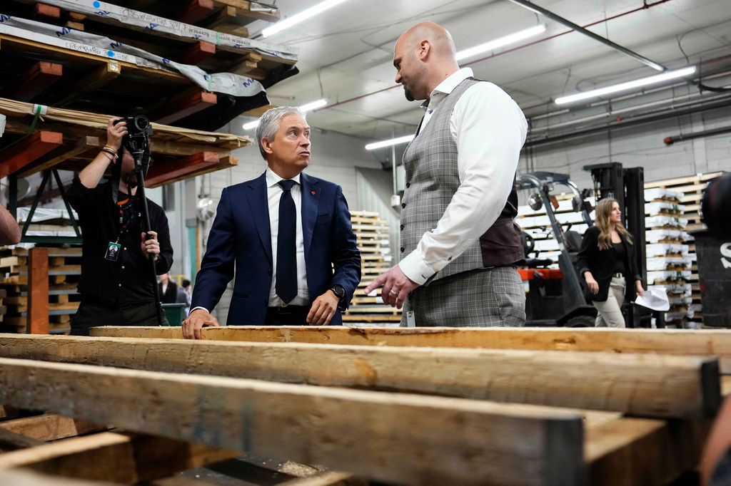 Canada Minister of Finance and National Revenue Francois-Philippe Champagne looks at Canadian lumber used for packaging products, as he speaks with Ideal Roofing co-CEO Philippe Laplante during a tour of the manufacturing plant in Ottawa, on Tuesday, Aug. 25, 2026. (Justin Tang/The Canadian Press via AP)