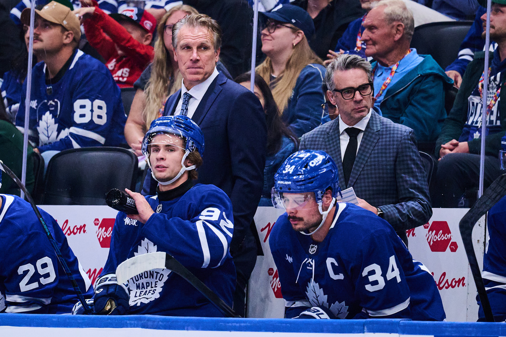 Toronto Maple Leafs head coach Jim Hiller, top left, looks on past Gavin McKenna (92), left, and Auston Matthews (34) during second period NHL pre-season hockey action against the Montreal Canadiens in Toronto, on Saturday, Sept. 19, 2026. (Sammy Kogan/The Canadian Press via AP)