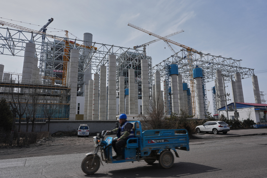 A motorist drives by part of Datong thermal project belonging to the Datong Coal Mine Group Co. Ltd. in Datong, China, Saturday, March 14, 2026. (AP Photo/Ng Han Guan)
