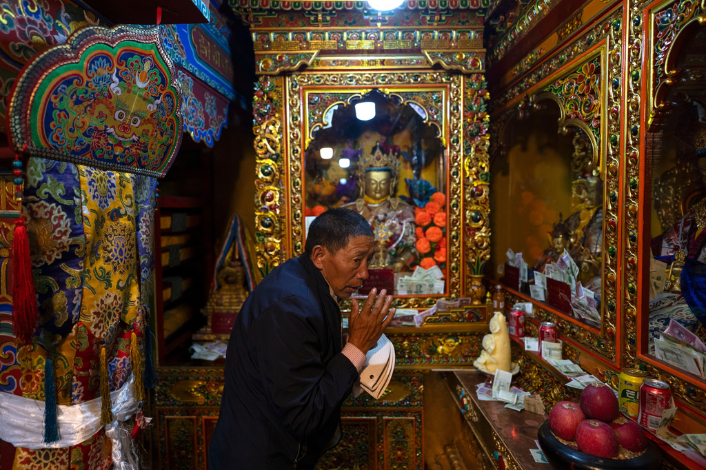 A visitor prays near inside the monastery of the Yumbulagang Palace, regarded as Tibet's first palace, in Shannan in western China's Tibet Autonomous Region on Thursday, July 23, 2026, as seen during a government organized visit for foreign journalists. (AP Photo/Ng Han Guan)