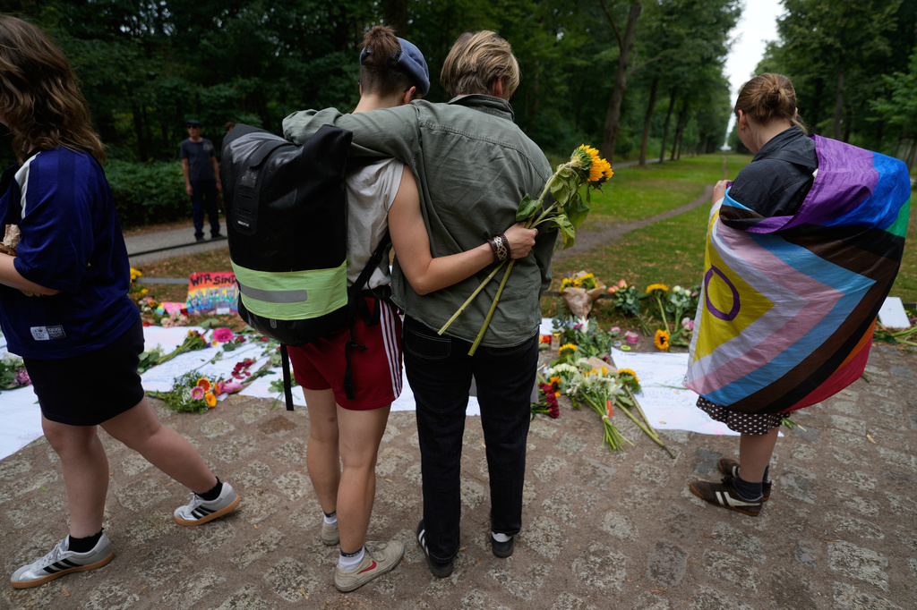 Two people hug at the memorial site commemorating the victims near the scene where a car rammed into a crowd at the Pride March in Berlin, Germany, Sunday, July 26, 2026. (AP Photo/Markus Schreiber)