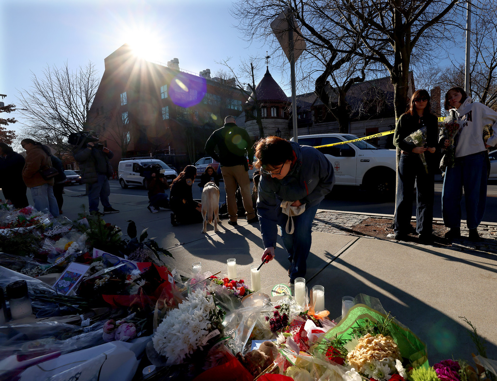 A woman lights a candle at a memorial set up in front of the Barus and Holley engineering building at Brown University in Providence, RI, Thursday, Dec. 18, 2025. (AP Photo/ Mark Stockwell)