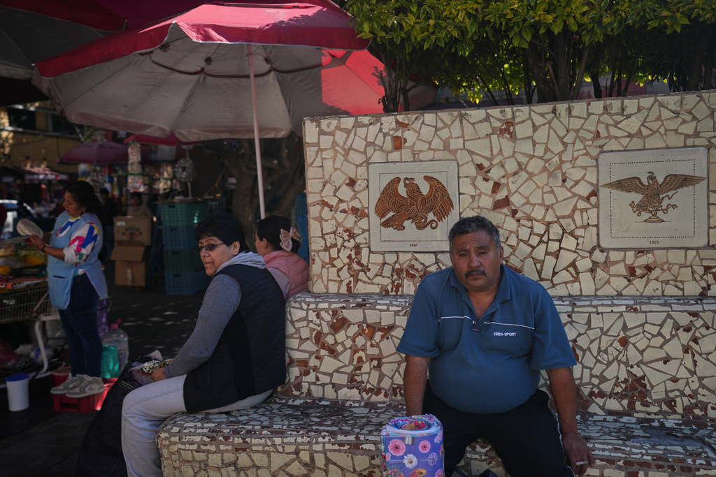 People sit on benches in Plaza del Aguilita, where the evolution of the Mexican coat of arms is showcased, Mexico City, Thursday, Nov. 13, 2025. (AP Photo/Claudia Rosel)