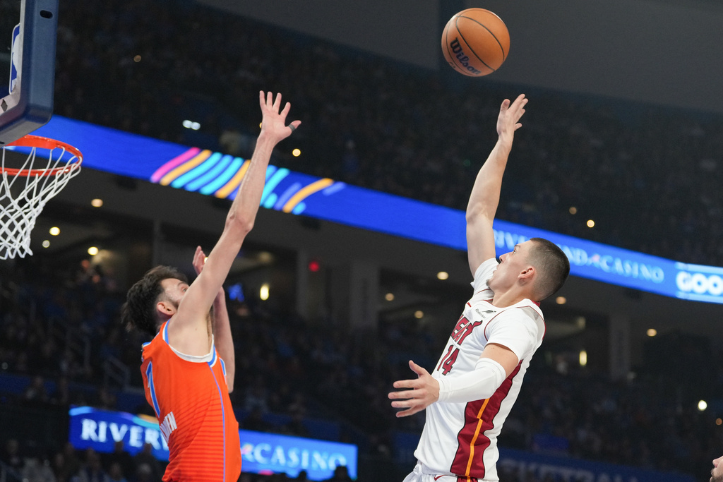 Miami Heat guard Tyler Herro, right, shoots over Oklahoma City Thunder center Chet Holmgren during the first half of an NBA basketball game, Sunday, Jan. 11, 2026, in Oklahoma City. (AP Photo/Kyle Phillips)