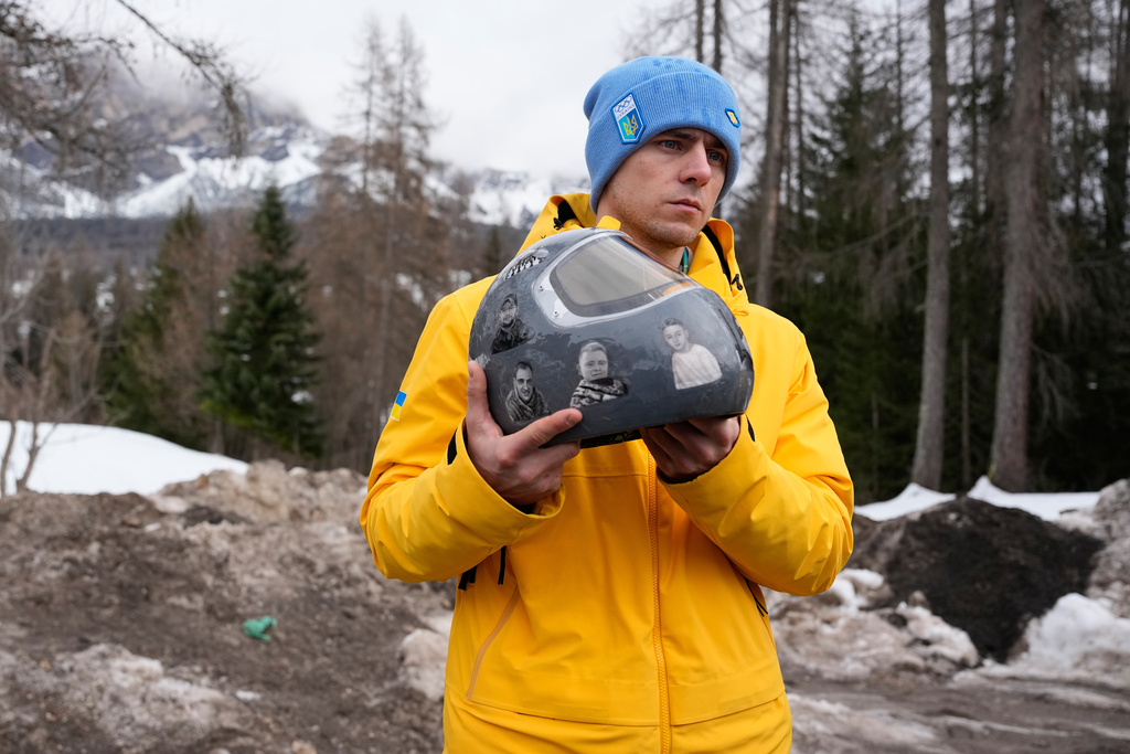 Ukrainian skeleton athlete Vladyslav Heraskevych holds his crash helmet as he stands outside the sliding center at the 2026 Winter Olympics, in Cortina d'Ampezzo, Italy, Thursday, Feb. 12, 2026. (AP Photo/Alessandra Tarantino)