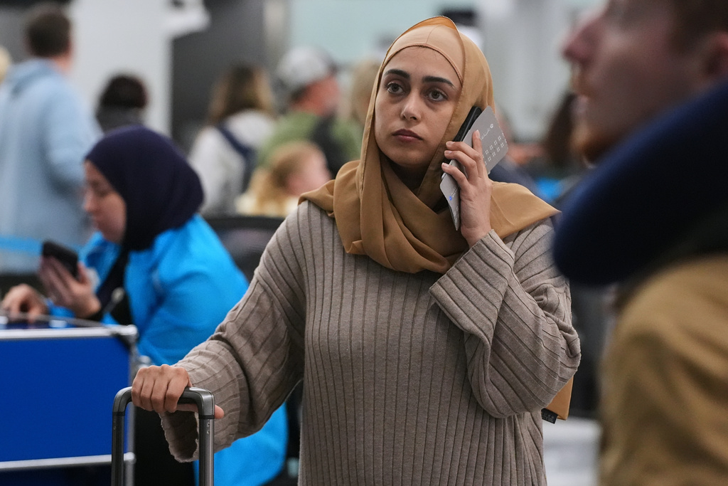 A traveler checks the status of her flight at the O'Hare International Airport in Chicago, Sunday, Nov. 30, 2025. (AP Photo/Nam Y. Huh)