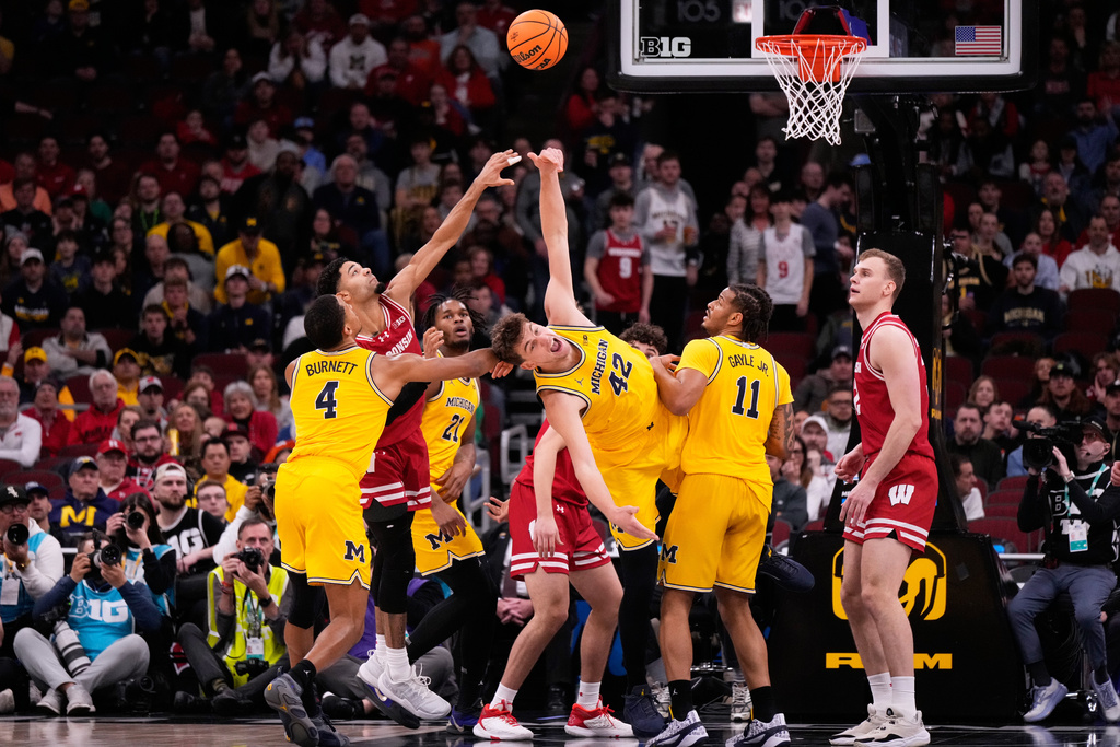 Wisconsin guard Nick Boyd, second from left, and Michigan forward Will Tschetter (42) battle for a rebound during the first half of an NCAA college basketball game in the semifinals of the Big 10 Conference tournament, Saturday, March 14, 2026, in Chicago. (AP Photo/Nam Y. Huh)