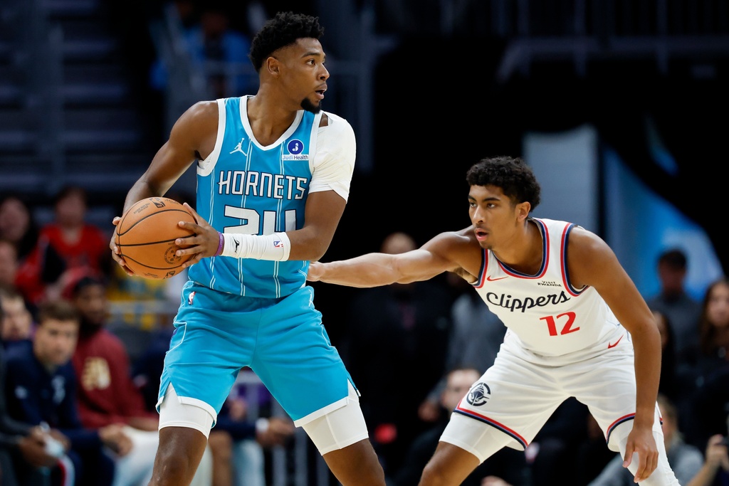Charlotte Hornets forward Brandon Miller, left, looks to pass as Los Angeles Clippers guard Cam Christie defends during the first half of an NBA basketball game in Charlotte, N.C., Saturday, Nov. 22, 2025. (AP Photo/Nell Redmond)