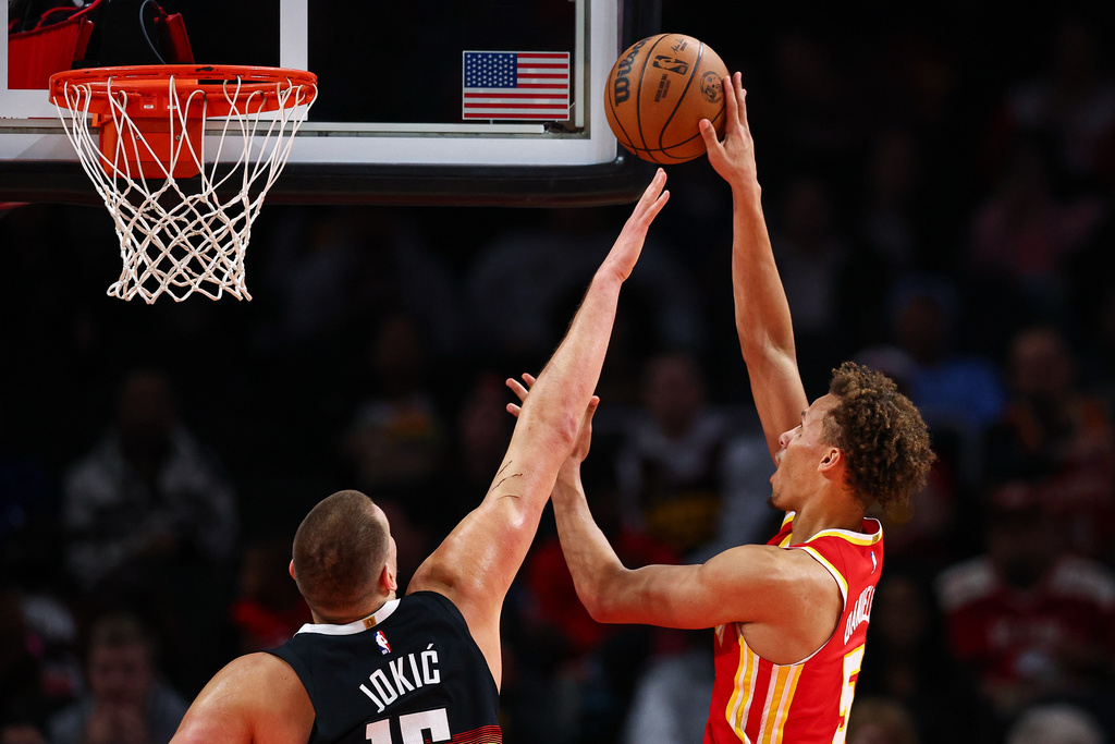 Atlanta Hawks guard Dyson Daniels, right, shoots the ball over Denver Nuggets center Nikola Jokic during the first half of an NBA basketball game, Friday, Dec. 5, 2025, in Atlanta. (AP Photo/Colin Hubbard)
